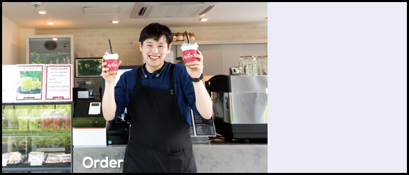 행복마루 로고가 적혀있는 커피컵을 양손으로 들고 웃고 있는 백진욱 매니저의 모습
